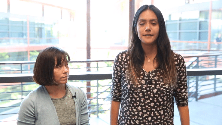 Moving gif image of white female faculty member and Latina graduate student standing inside the Clark Center talking.