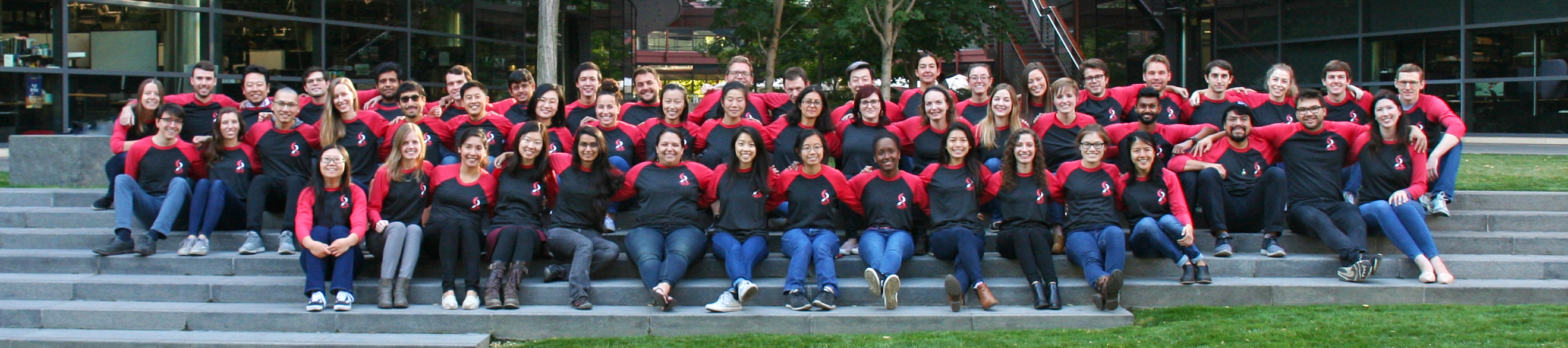 Photo of dozens of Stanford graduate students standing together at the Clark Center wearing matching apparel.