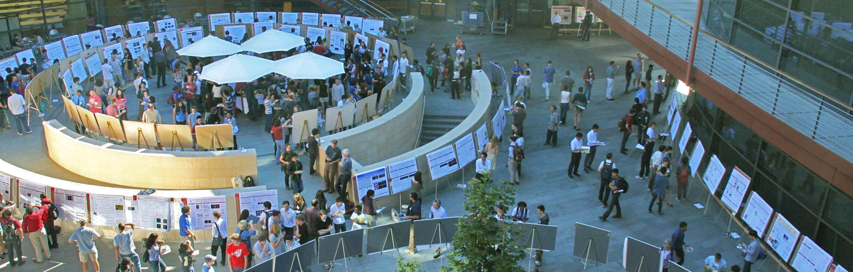 Photo taken from above of the Clark Center, with the courtyard filled with scientific posters and people looking at them.