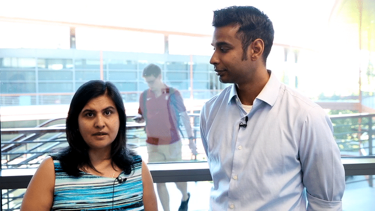 Moving gif image of a South Asian female faculty member and a South Asian male faculty member standing together in the Clark Center, talking to the camera.