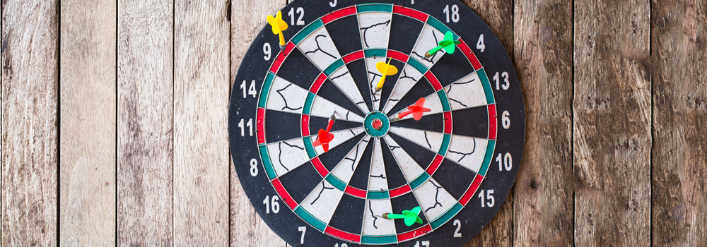 Photo of a dart board with several darts in it.