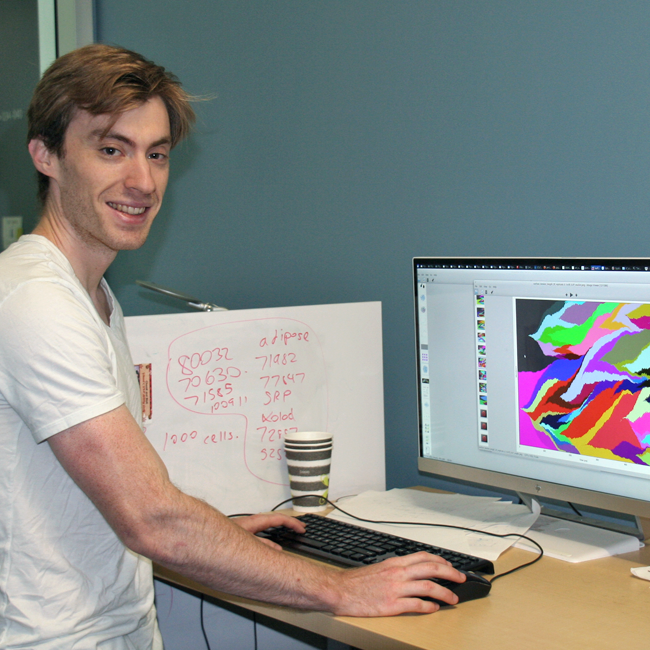 Photo of graduate student Alec Tarashansky in the lab, working at a computer with a colorful display.