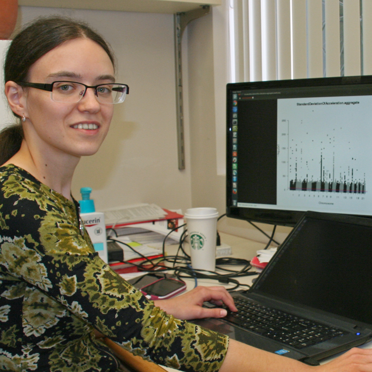 Photo of graduate student Anna Shcherbina in the lab, displaying a graph on her computer screen.