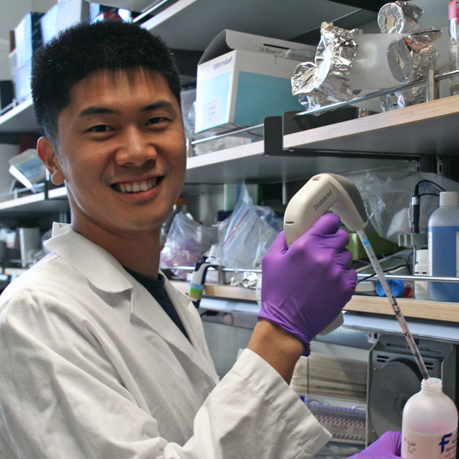 Photo of graduate student Binbin Chen in the lab, pipetting a pink solution.