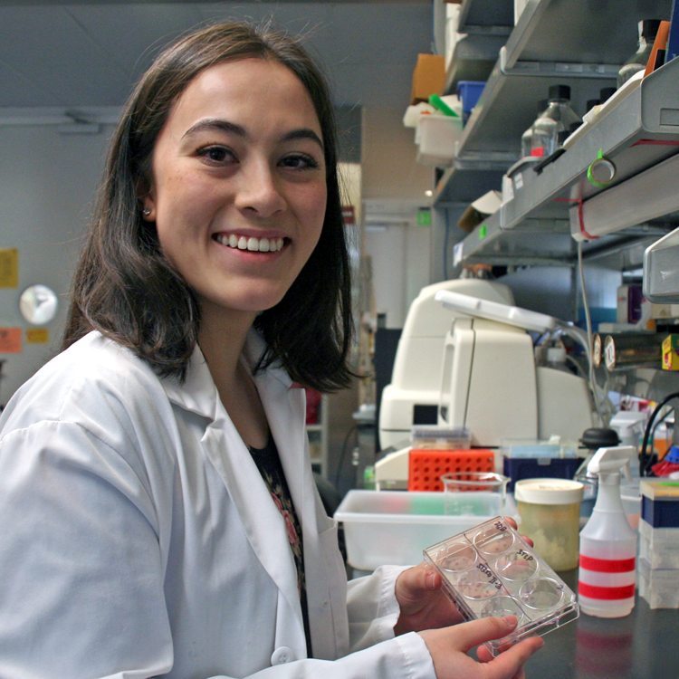 Photo of USRP student Clare Moffatt in the lab, holding up a tray of cultures.