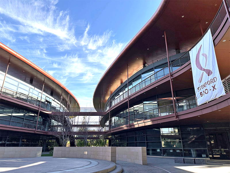 Outdoor photo of the Clark Center Courtyard showing the Stanford Bio-X logo on a large banner.