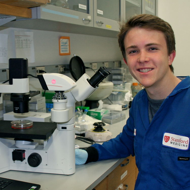 Photo of USRP student Collin Schlager in the laboratory, working with a large microscope.