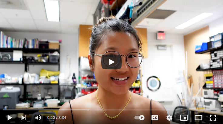 Screenshot of a YouTube video, showing undergraduate Grace Soontornviwath, a female Asian undergraduate student, in of a wet lab area, wearing glasses and smiling.