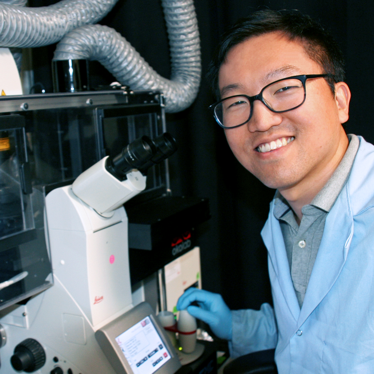 Photo of graduate student Hong-pyo Lee in the lab, using a large microscope.