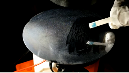Screenshot showing researcher's gloved hand, raising a small paper test stick that shows blue at the end after being swiped across a surface with condensation.