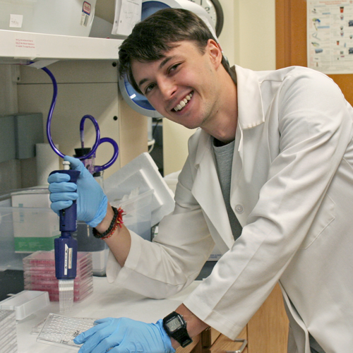 Photo of student Jan Sokol at a lab bench, using a pipette.