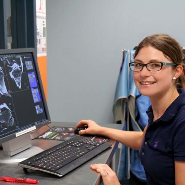 Photo of graduate student Mary Hall in the lab, working at a laptop showing bone scan images.
