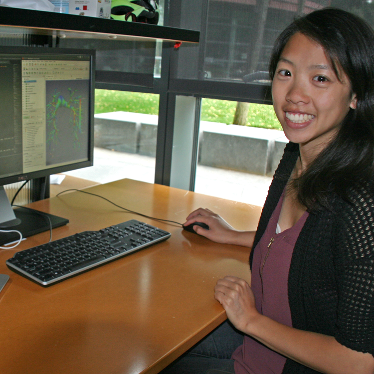 Photo of graduate student Melody Dong in the lab, displaying an image of vasculature models on a computer screen.