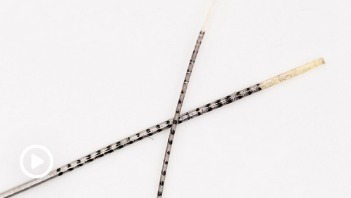 Screenshot of video with play button, showing two tiny wires on a pale background.