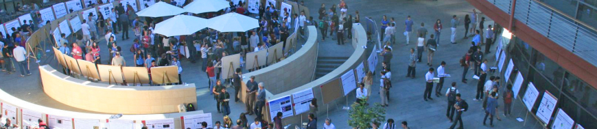 View from above of a conference with people walking and posters displayed.