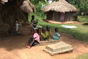 Photo by Dr. Manu Prakash: Children in Uganda sit at the graves of two of their siblings buried side by side. Both were likely victims of infectious disease.
