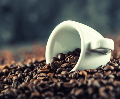 Photo of coffee cup surrounded by coffee beans.