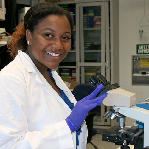Photo of undergraduate student Sierra Porter standing beside a large microscope.