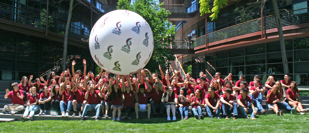 Group photo of 2017 students in red shirts, bouncing a huge white ball with Bio-X logos on its sides.