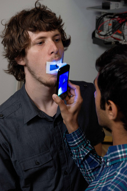 Photo of Dhruv Boddupalli demonstrating the OScan oral scanner on James Clements.