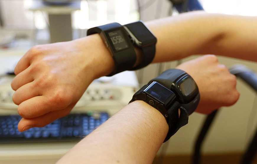 Photo of a subject's two hands, with each wrist wearing two wearable sensor devices.