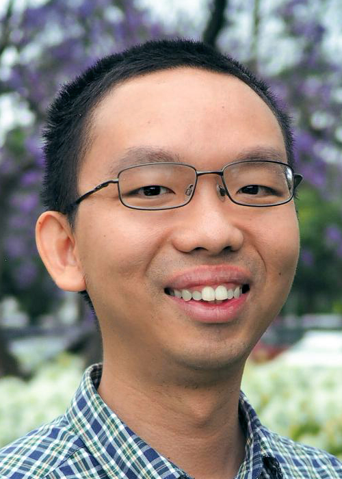 Photo of a smiling Asian male faculty member outdoors. He is wearing glasses.