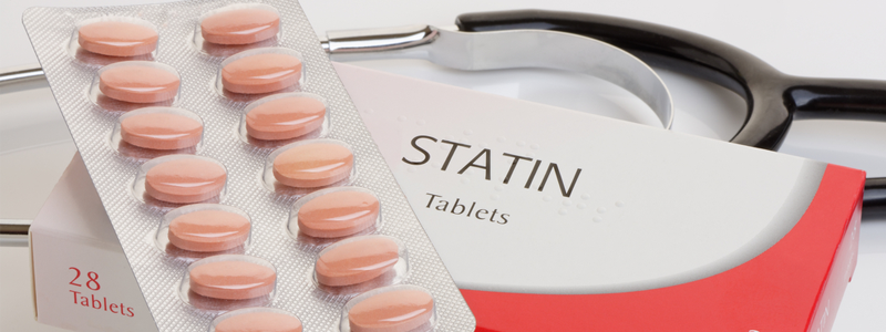 Photo of a packet of pink statin pills on top of a labeled box, with a stethoscope in the background.
