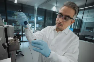 Photo of male faculty member in the laboratory with a pipette.