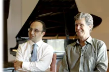 Drs. Josef Parvizi and Chris Chafe sitting next to each other in front of a piano.