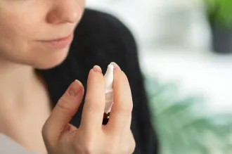 Photo of a woman raising a nasal spray in her hand.