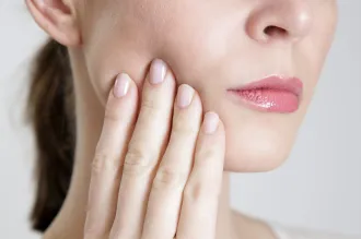 Stock photo of a woman touching her cheek.