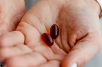 Photo of cupped hands with two large orange-brown pills held in the palms.