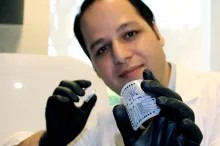 Photo of engineering research associate Rahim Esfandyarpour holding up and flexing small lab on chip device.