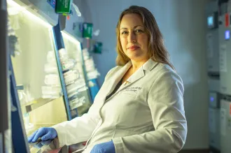 Photo of Dr. Michelle Monje seated in the laboratory, wearing a lab coat.