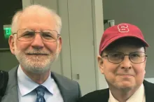 Photo of elder doctor and middle-aged man wearing a red hat.