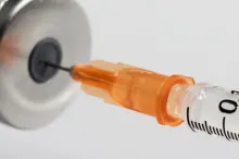 Photo of a needle going into a vaccine container.