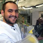 Indoor photo of a Latino male graduate student in a wet lab.