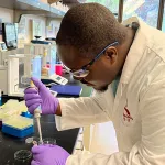 Indoor photo of a Black male graduate student in a wet lab.
