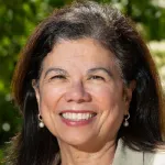 Outdoor headshot photo of a smiling female faculty member, Dr. Yvonne Maldonado, Professor of Pediatrics at Stanford University.