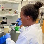 Indoor photo of a Black female graduate student in a wet lab.