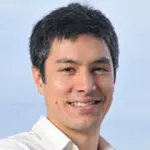 Photo of a smiling part-Asian male faculty member outdoors, Dr. Kerwyn Casey Huang, Professor of Bioengineering and Microbiology & Immunology at Stanford University.