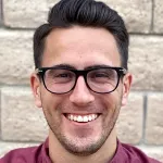 Outdoor headshot photo of a smiling white male graduate student, Nicholas Rommelfanger.