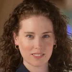 Outdoor headshot photo of a smiling female faculty member with long curly hair, Dr. Sherri Rose, Professor of Health Policy at Stanford University.