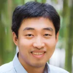 Outdoor headshot photo of a smiling male Asian faculty member, Dr. Yan Xia, Associate Professor of Chemistry at Stanford University.