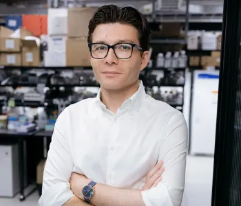 Indoor photo of a male faculty member standing inside of a wet laboratory.