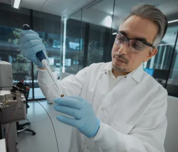 Photo of male faculty member in the laboratory with a pipette.