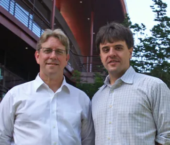 Outdoor photo of two male faculty members standing together and smiling.