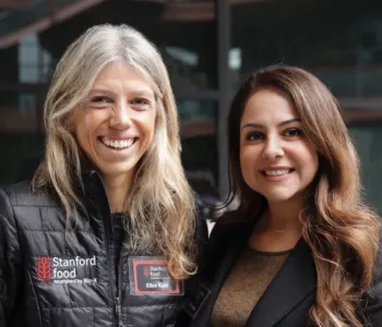 Photo of two women standing together outdoors, smiling at the camera.
