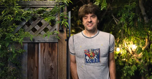 Outdoor nighttime photo of Karl Deisseroth leaning against a wooden gate.