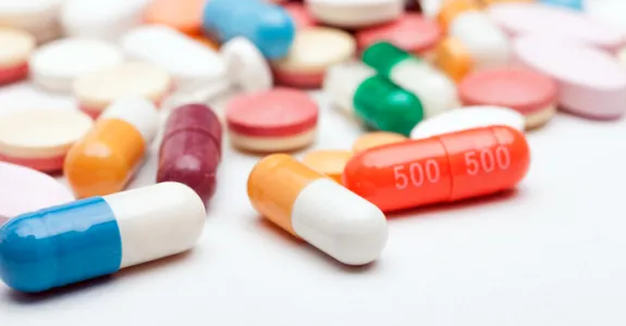 Photo of an assortment of colorful pills spilled across a white surface.